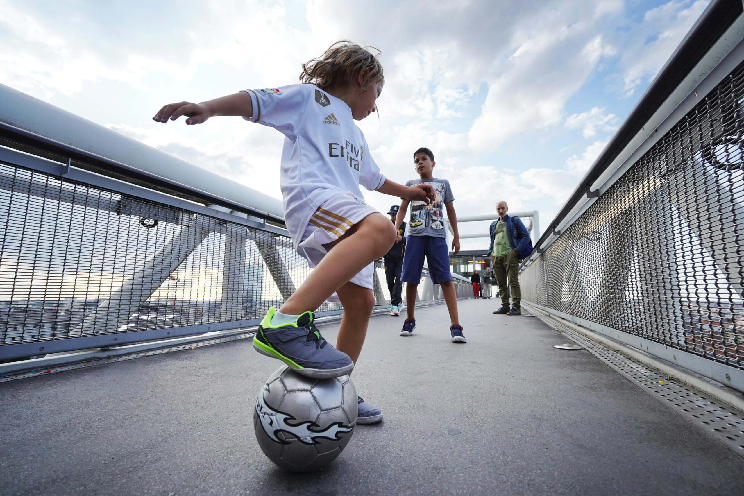 Enfants jouant au football sur une passerelle urbaine, symbolisant le recrutement de talents, l’énergie et le développement du potentiel.
